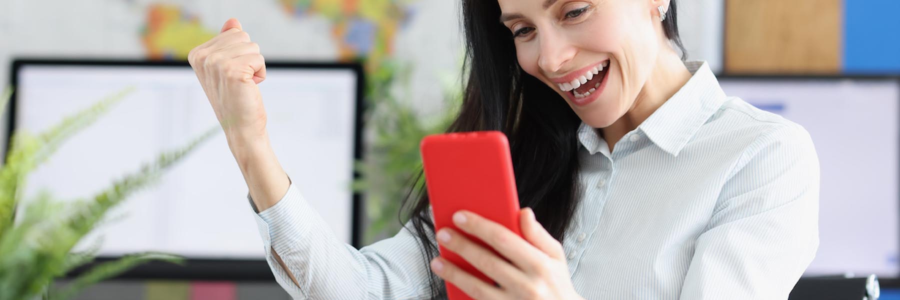 Excited employee celebrating while looking at their phone, symbolizing increased engagement and satisfaction with enhanced benefits.